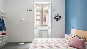 A bedroom with a bed, a window, a radiator, a wardrobe, and a wall-mounted shelf. - Casa Roma al Centro di Palermo by Wonderful Italy (Palermo)