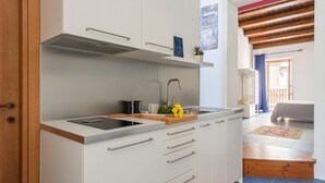 Una cocina moderna con armarios blancos, un lavamanos de acero inoxidable y una encimera de madera.