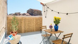 Una terraza con mesa y sillas, una cesta y un florero con flores.