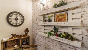 A rustic interior with a brick wall, a clock, and shelves labeled 'Flowers,' 'Spices,' and 'Vegetables.' - Corte Galluzzi in Basilica by Wonderful Italy (Bologna)