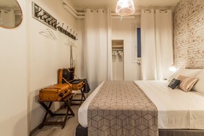 A hotel room with a bed, a suitcase, a coat rack, and a wardrobe. - Corte Galluzzi in Basilica by Wonderful Italy (Bologna)