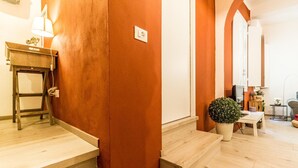A staircase leading to a room with a wooden floor and a red wall. There is a small table with a lamp and a plant on the landing. - Corte Galluzzi in Basilica by Wonderful Italy (Bologna)