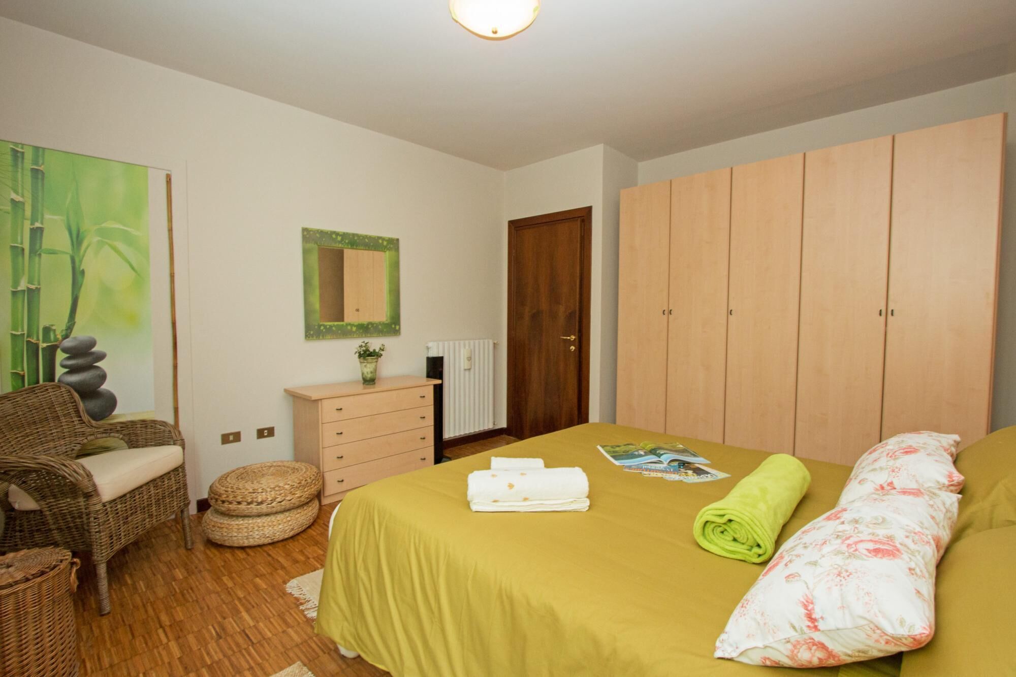 A bedroom with a bed, a dresser, a chair, a mirror, and a wardrobe.