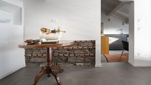 Een moderne keuken met een accentmuur van steen, een houten tafel met een decoratief object, en een zwarte stoel.
