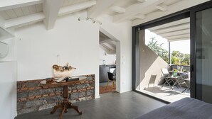 Een modern interieur met een stenen accentmuur, een houten tafel met decoratieve objecten, en een uitzicht op een terras door een glazen deur.