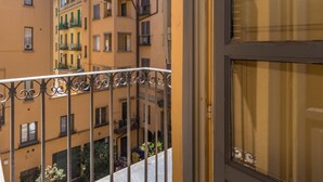 Blick von einem Balkon mit Metallgeländer auf eine Reihe mehrstöckiger Gebäude mit Balkonen und Fenstern.