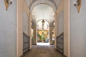 A corridor with arches, a hanging light fixture, and a view of the outside. - San Carlo Apartment by Wonderful Italy (Turin)