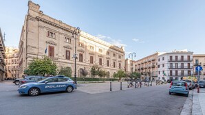 A street with a police car, buildings, and a clear sky. - Casetta Borsa by Wonderful Italy (Palermo)