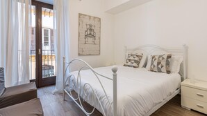A bedroom with a bed, a nightstand, a window with curtains, and a door leading to a balcony. - Casetta Borsa by Wonderful Italy (Palermo)