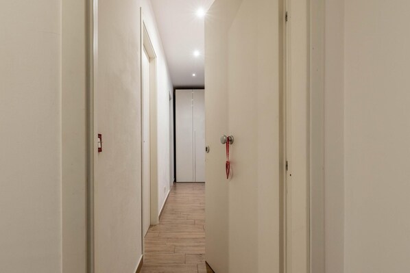 A narrow hallway with wooden flooring and white walls. - Casetta Borsa by Wonderful Italy (Palermo)
