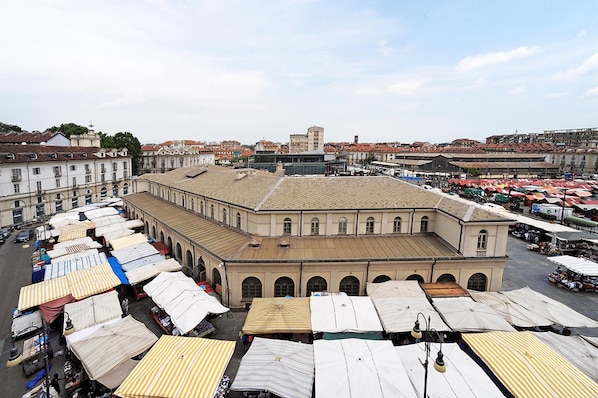A large building with multiple covered market stalls in front.