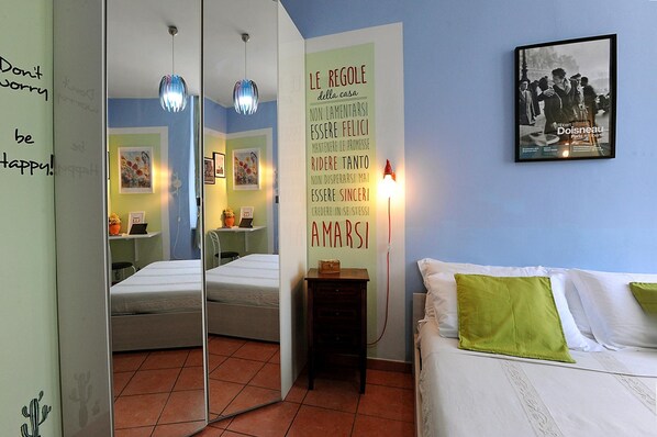 Une chambre à coucher comprenant un lit, un miroir, une table de chevet et un mur orné d’un texte motivant.