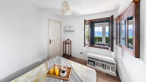 A bedroom with a bed, a bedside table with breakfast items, a window with a view, and a radiator. - Residence San Giorgio PT 3 by Wonderful Italy (Toscolano Maderno)