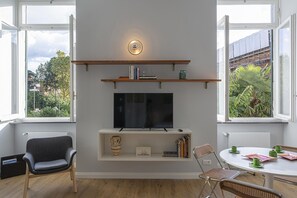 A modern living room with a TV, bookshelves, and a dining area with chairs and a table. - Modern Loft in the Center by Wonderful Italy (Genoa)