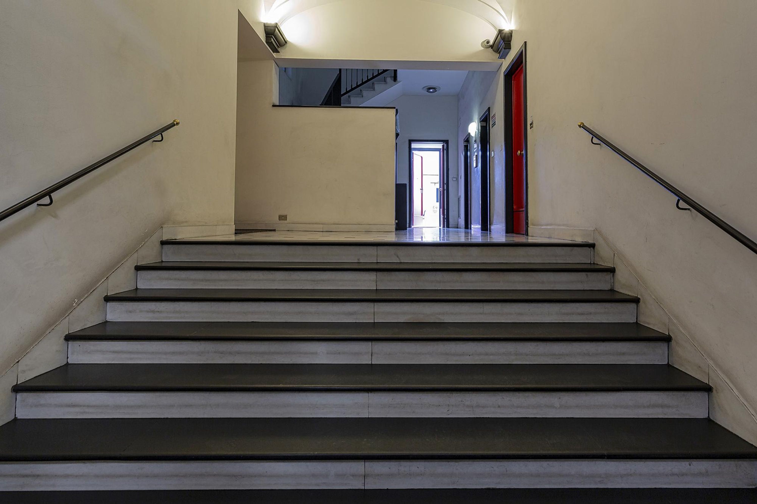 A staircase with handrails, leading to an open door at the top.