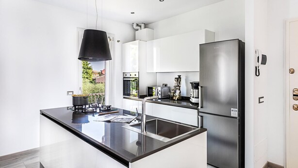 A modern kitchen with a black countertop, stainless steel appliances, and white cabinetry. - Il Quadrifoglio D4 con Piscina by Wonderful Italy (Sirmione)