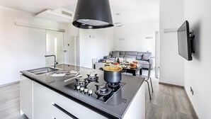 A modern kitchen with a central island, a built-in stove, and a large black overhead vent. - Il Quadrifoglio D4 con Piscina by Wonderful Italy (Sirmione)