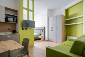 Cozy living space with a dining table, sofa, and flat-screen TV, plus a kitchenette and wardrobe.