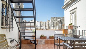 A balcony with a metal staircase, potted plants, a wooden bench, and a table. - Le Terrazze Dell Olivo by Wonderful Italy (Syracuse)