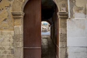 Explore the historic corridor with a wooden door and stone walls, featuring a staircase leading to more.