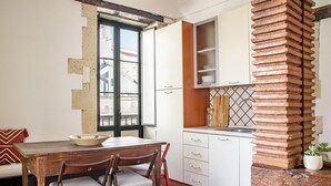A kitchen with white cabinets, a wooden table, and a brick column. - Le Terrazze Dell Olivo by Wonderful Italy (Syracuse)