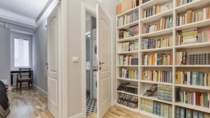 A room with a large bookshelf filled with books, a wooden floor, and a door leading to another room. - Marvelous Soziglia Apartment by Wonderful Italy (Genoa)