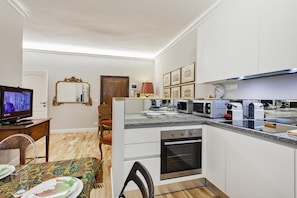 Eine kompakte Küche mit Mikrowelle, Backofen und einer Essecke mit Tisch für zwei Personen.