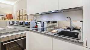 A modern kitchen with white cabinets, granite countertops, a built-in oven, a stainless steel range hood, and a double sink. - Marvelous Soziglia Apartment by Wonderful Italy (Genoa)