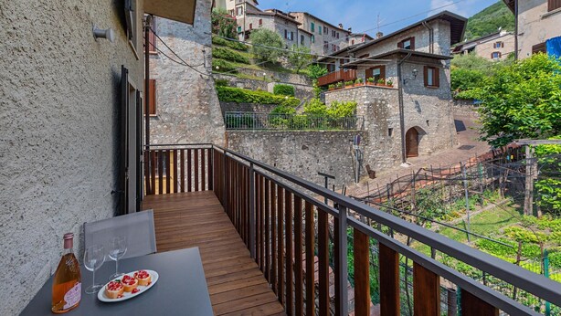 A balcony with a table and chairs, overlooking a hillside with traditional stone buildings. - Lemon House 2 Apartment by Wonderful Italy (Gardone Riviera)