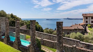 A stone wall with a pool, overlooking a body of water and distant land. - Lemon House 2 Apartment by Wonderful Italy (Gardone Riviera)