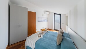A bedroom with a bed, a wardrobe, a small table with a tray, and a window with a view. - Lemon House 2 Apartment by Wonderful Italy (Gardone Riviera)