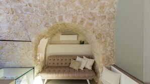 A cozy room with a stone wall, a cushioned bench, and a glass table.