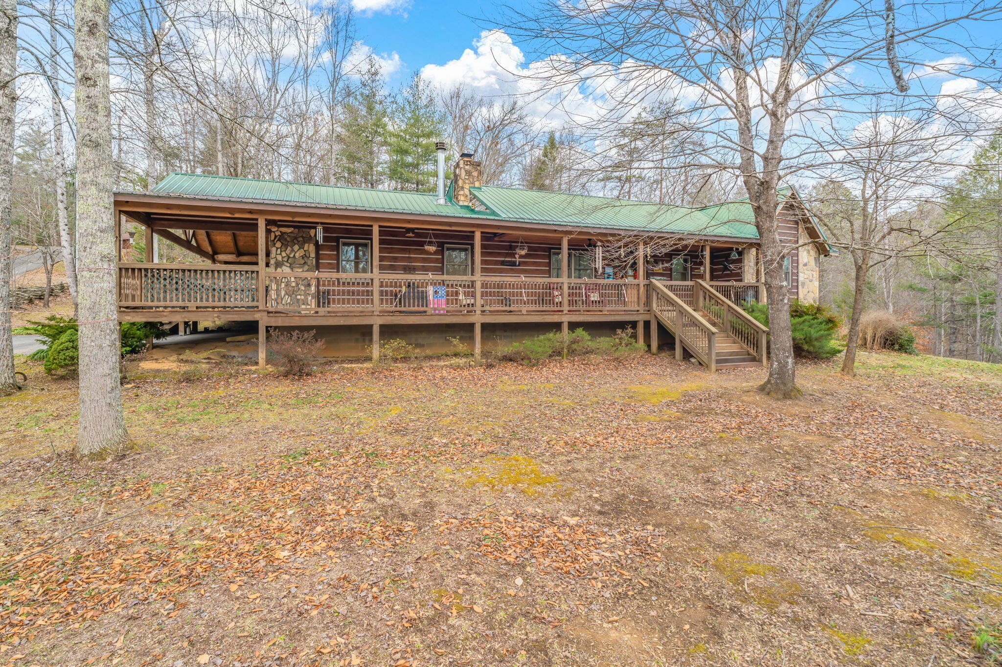 A cabin with a green roof, wooden deck, and a chimney.