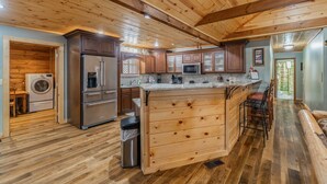 Una cucina con mobili in legno, un'isola centrale, elettrodomestici in acciaio inossidabile e una lavatrice integrata.