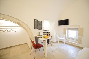 Ein Essbereich mit Tisch, Stühlen, Obstschale, Kaffeemaschine und einer Speisekarte.