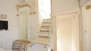 A spacious room with a large TV, a glass door, and a staircase leading to another level. - Scirocco Apartment With Terrace by Wonderful Italy (Ostuni)