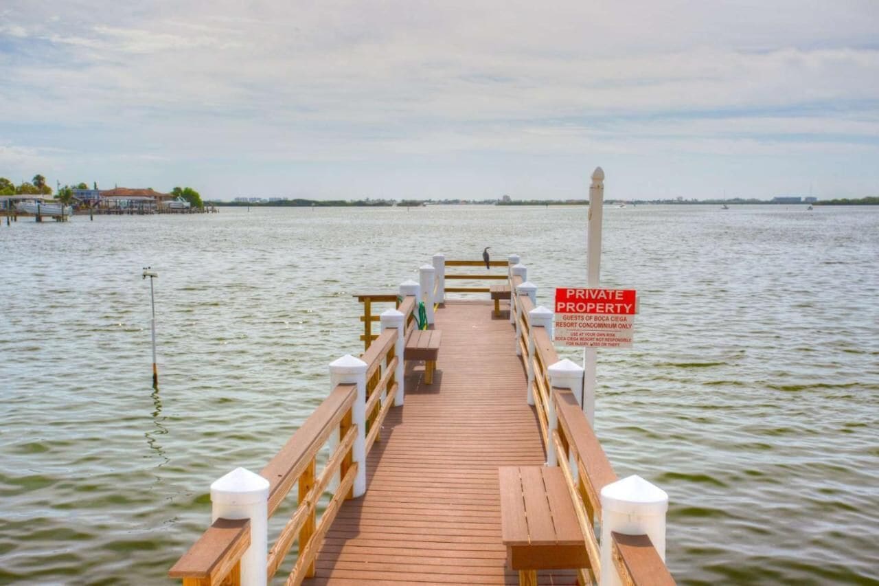 A wooden pier extending into calm water with a sign indicating private property.