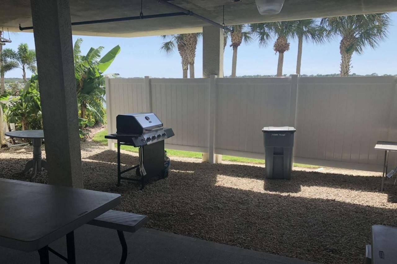 An outdoor patio area with a barbecue grill, a trash can, and tables.