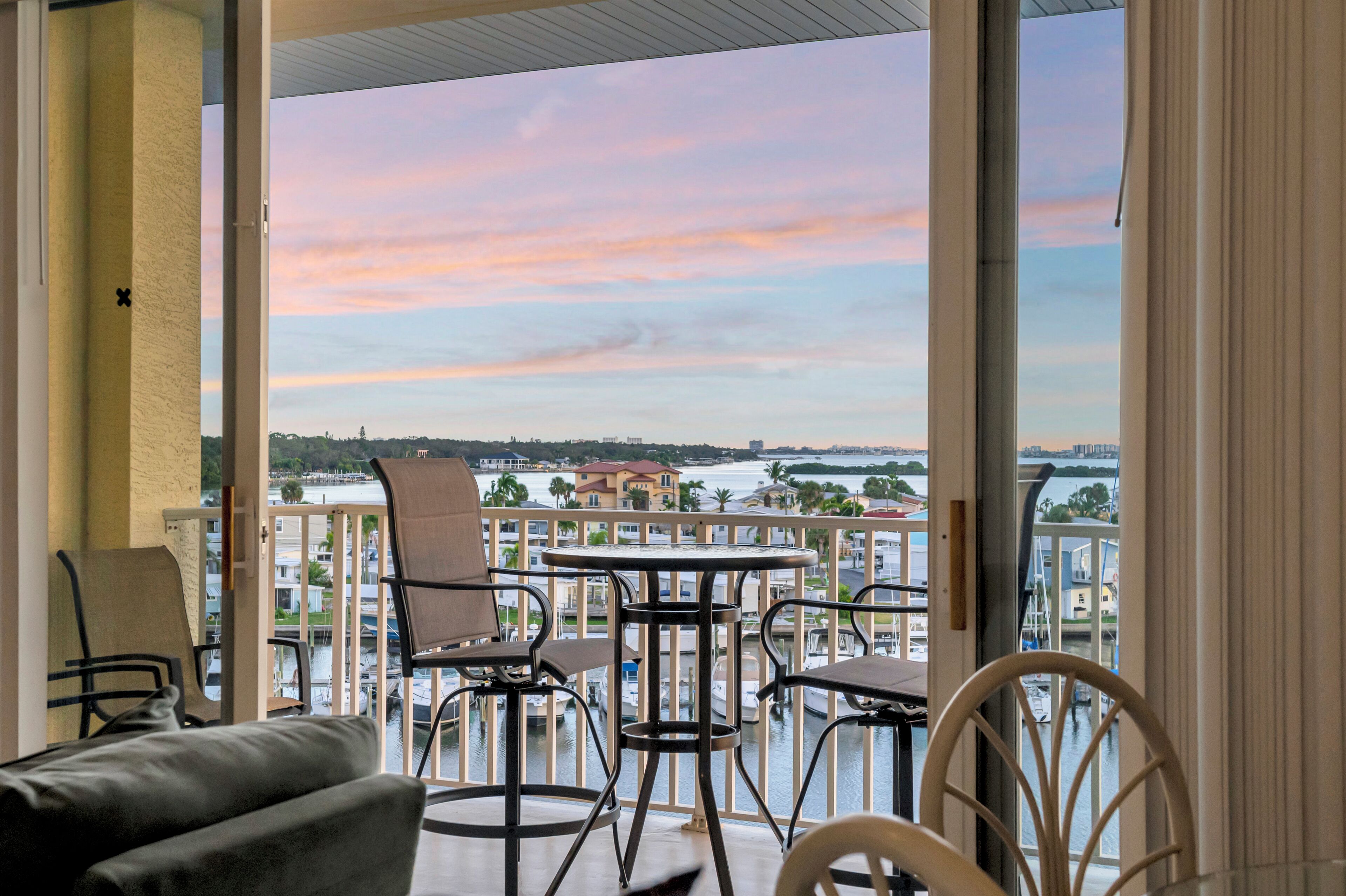 Un balcón con vistas a un puerto deportivo y al paisaje urbano al atardecer.