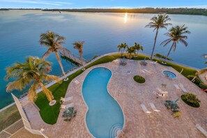 Ein Pool mit gewelltem Rand, umgeben von Palmen und Liegestühlen.