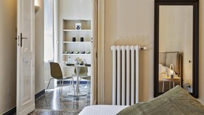 Een hotelkamer met een bed, een stoel, een klein tafeltje en een radiator.