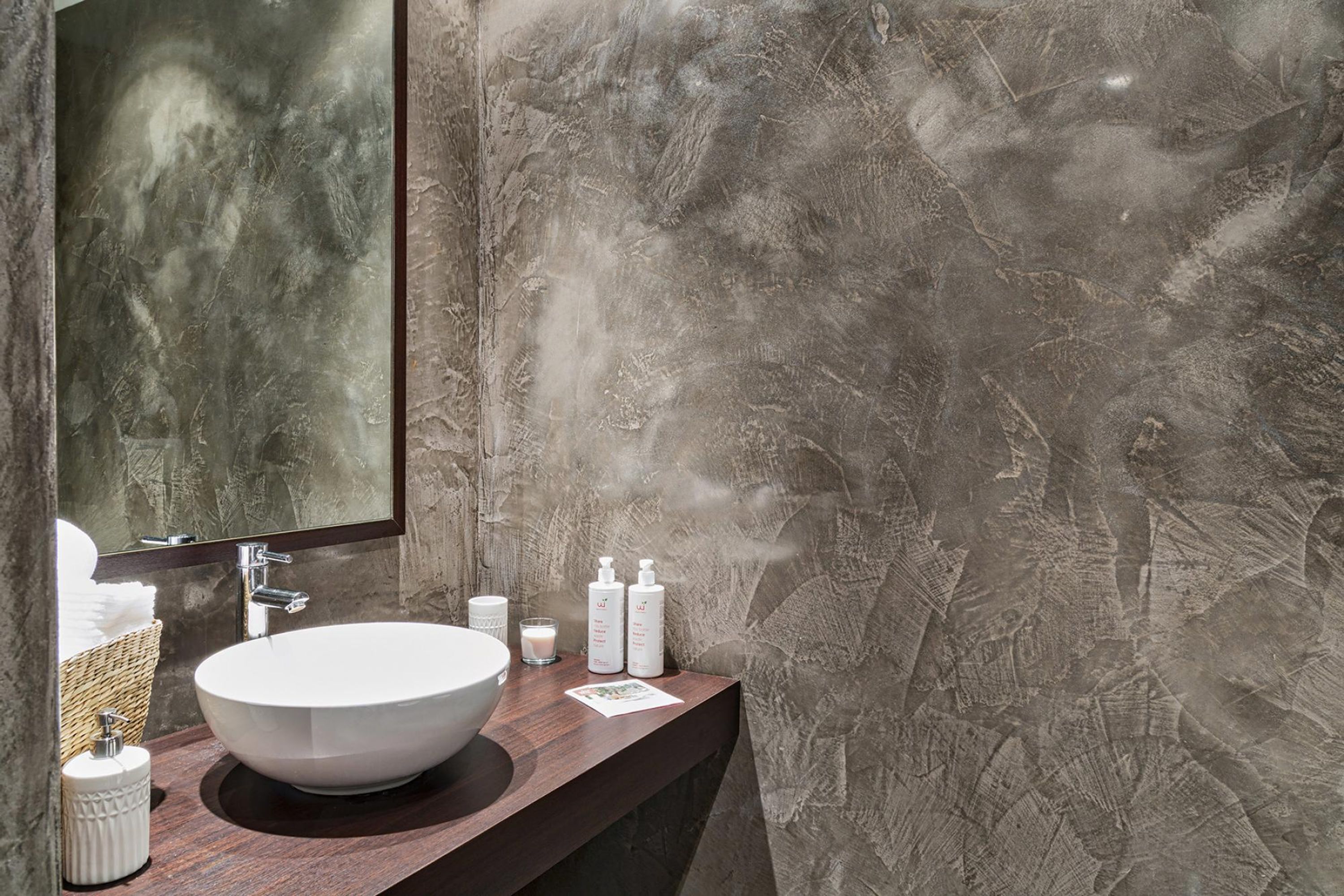 Une salle de bain avec un grand lavabo blanc, un miroir et un mur à motifs.