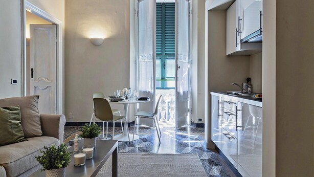 Een modern appartement met een eethoek, kitchenette en woonkamer met een bank en een salontafel.
