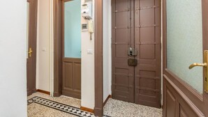Un corridoio con due porte in legno, una delle quali con un vetro, e un pavimento decorato.