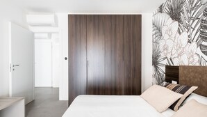 A bedroom with a large bed, a wooden wardrobe, and a wall with a tropical leaf pattern. - Ariosti Apartment I by Wonderful Italy (Bologna)
