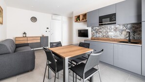 A modern kitchen with grey cabinets, a wooden dining table, and black chairs. - Ariosti Apartment I by Wonderful Italy (Bologna)