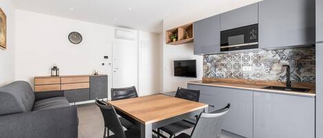 A modern kitchen with grey cabinets, a wooden dining table, and black chairs.