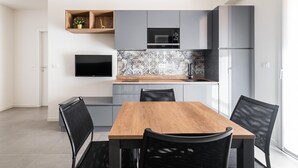 A modern kitchen with grey cabinets, a wooden dining table, and black chairs. - Ariosti Apartment I by Wonderful Italy (Bologna)