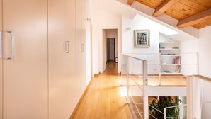 A modern interior with a wooden ceiling, a staircase, and a white wall with a painting.