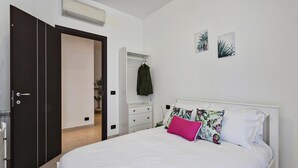 Une chambre à coucher comprenant un lit, une armoire, une table de chevet et un climatiseur fixé au mur.